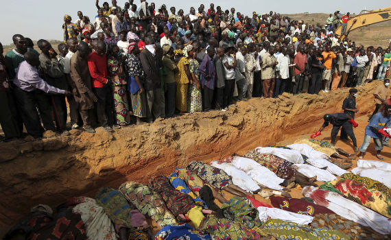 Mass Grave in Africa with a large amount of people looking on.
